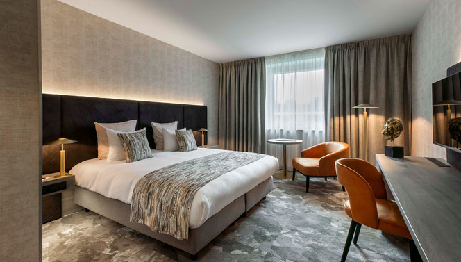 Salon élégant et cosy avec bureau dans la chambre Deluxe de l’hôtel Van der Valk à Waterloo.